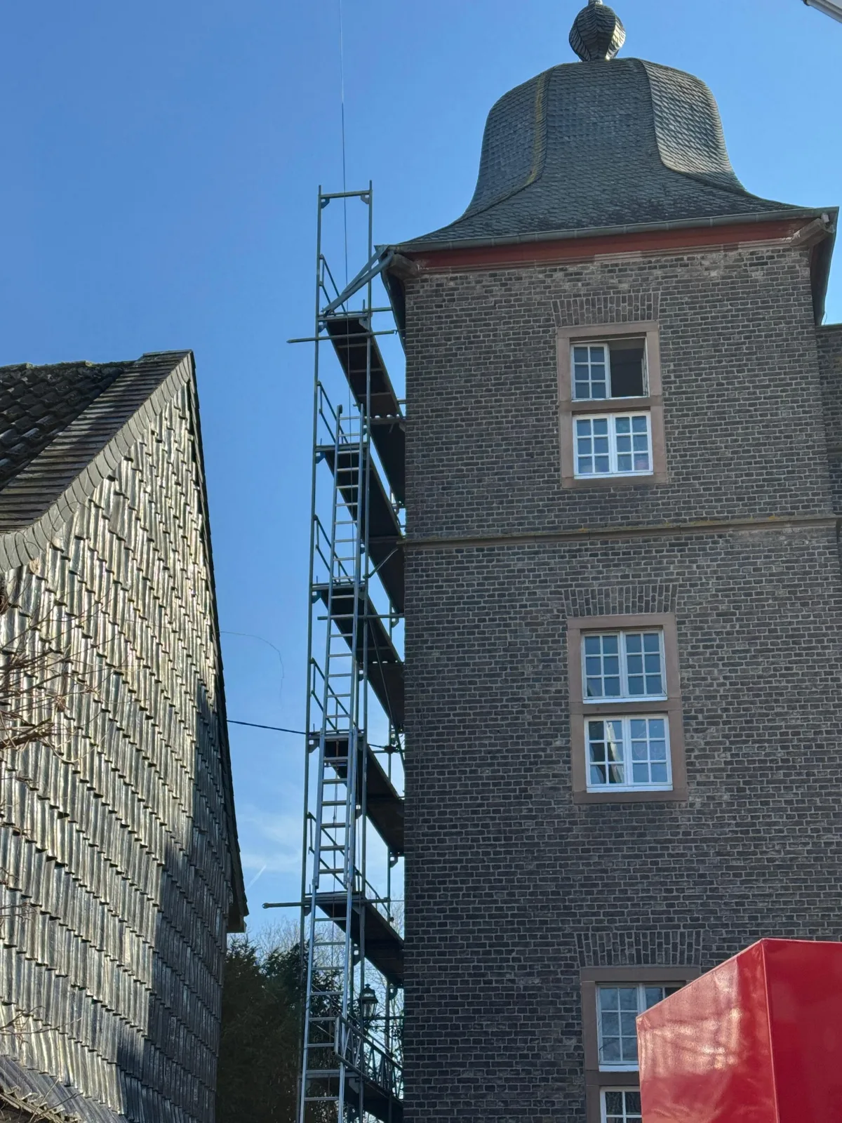 Hohes Klinkergebäude, an einer verkleideten Wand steht ein Gerüst